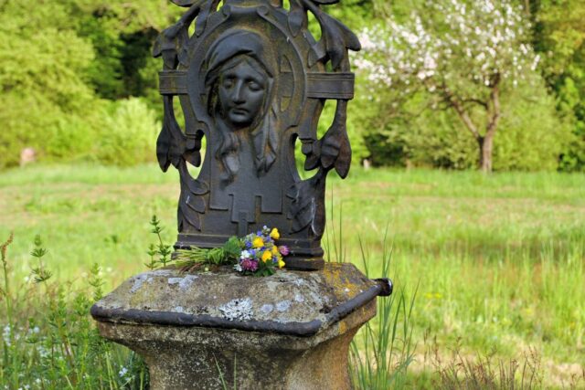 Křížek u cesty dozdobený květinami